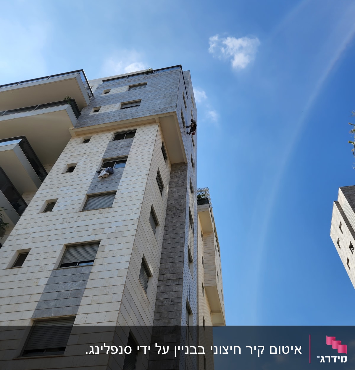 אדם מטפס על קיר בניין גבוה עם חבלים